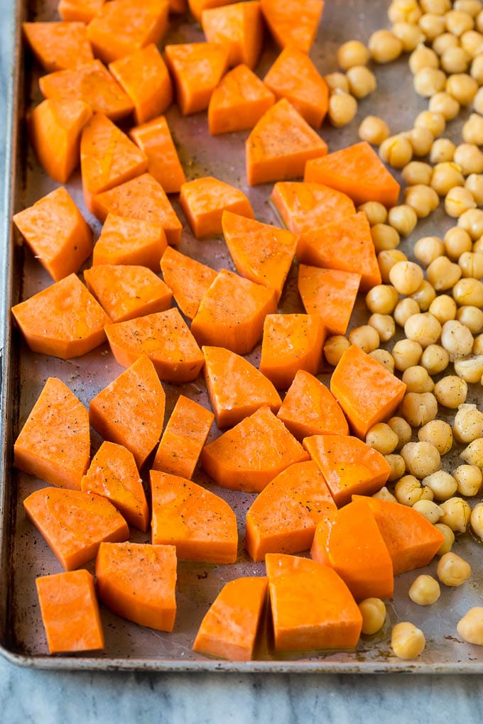 Receta del cuenco de Buda |  Cuenco de Buda vegano |  Cuenco de quinua |  Receta de camote |  Receta de quinua #salud #limpieza #quinoa #dinner #Cazuelas online#ceci Patatas dulces crudas enlatadas y garbanzos en una bandeja para hornear.