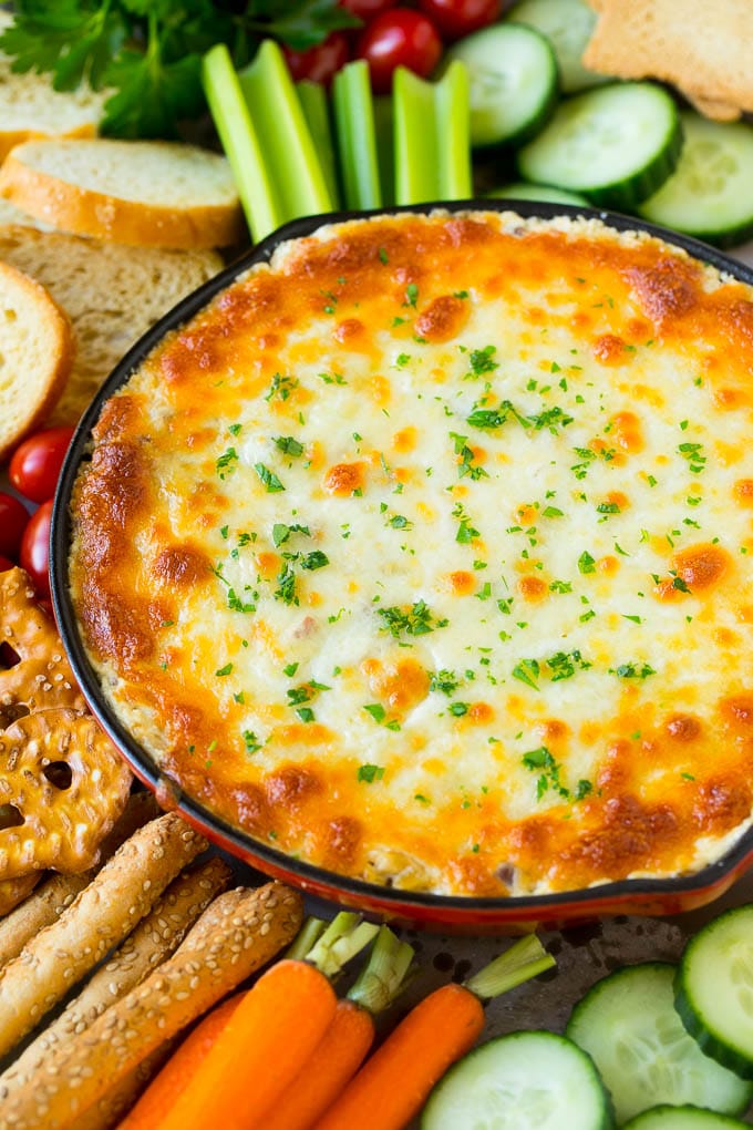 Reuben Dip al horno en una sartén servido con galletas saladas y verduras.