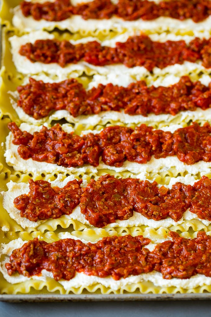 Fideos de lasaña cubiertos con ricotta y salsa de carne.