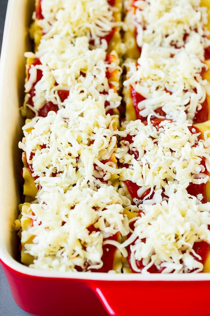 Fideos de lasaña envueltos en una fuente para horno y cubiertos con salsa y queso derretido.