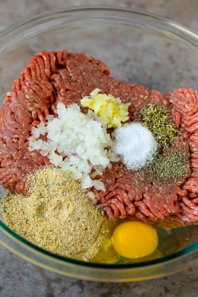 Carne molida con cebolla, pan rallado y condimentos en un tazón.