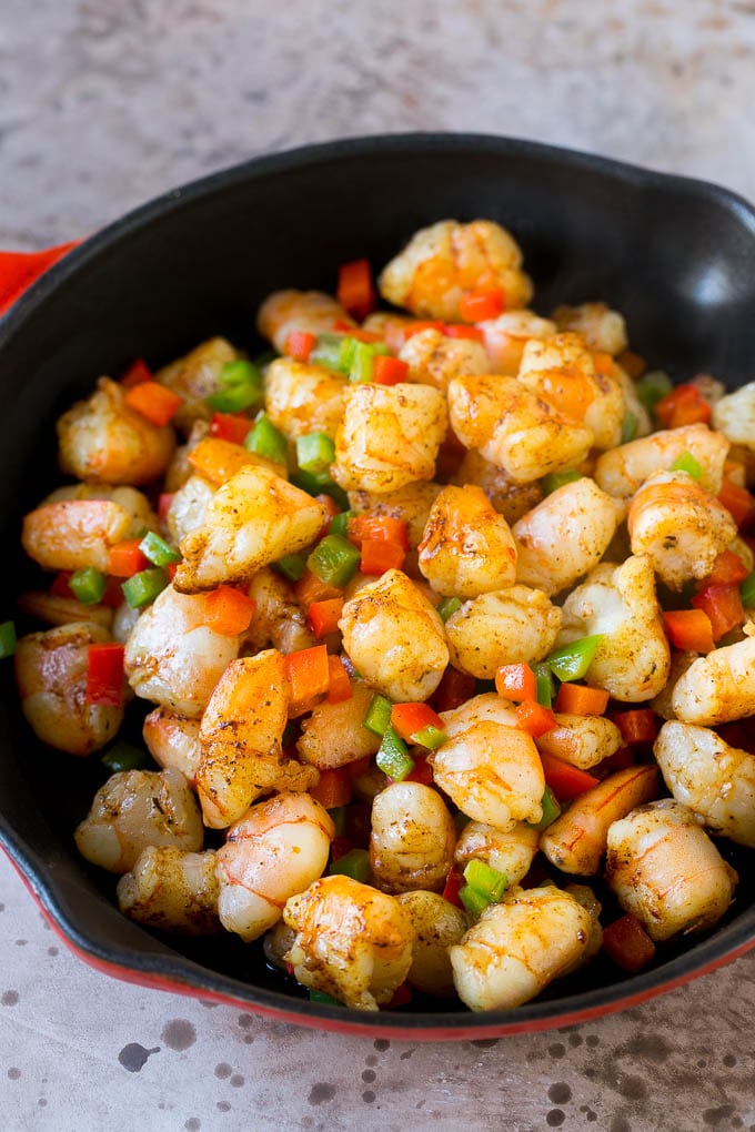 Una sartén llena de camarones y pimientos picados.