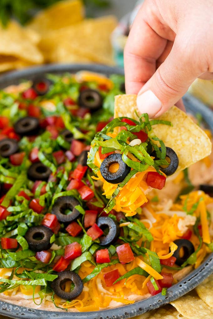Mano que sostiene el chip de tortilla cubierto con salsa de taco.