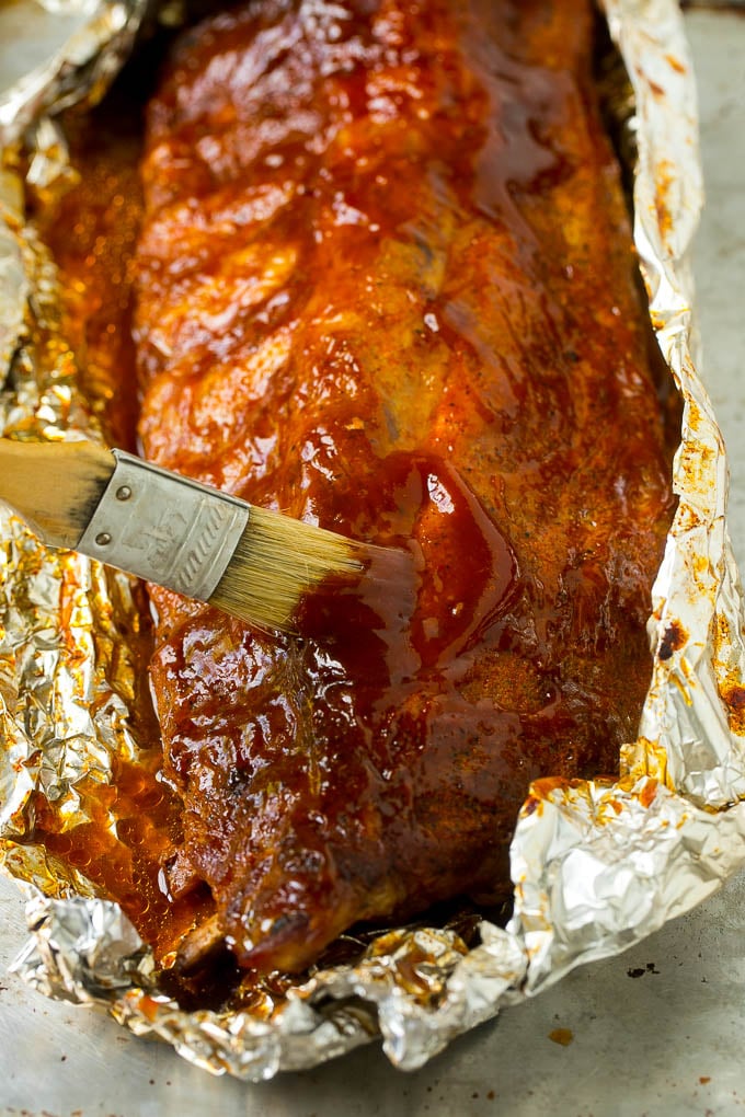 Receta de costillas ahumadas | Costillas posteriores | Costillas de cerdo # cerdo # costillas # fumador # cena #dinneratthezoo Un pincel espolvoreando las costillas ahumadas con salsa barbacoa.