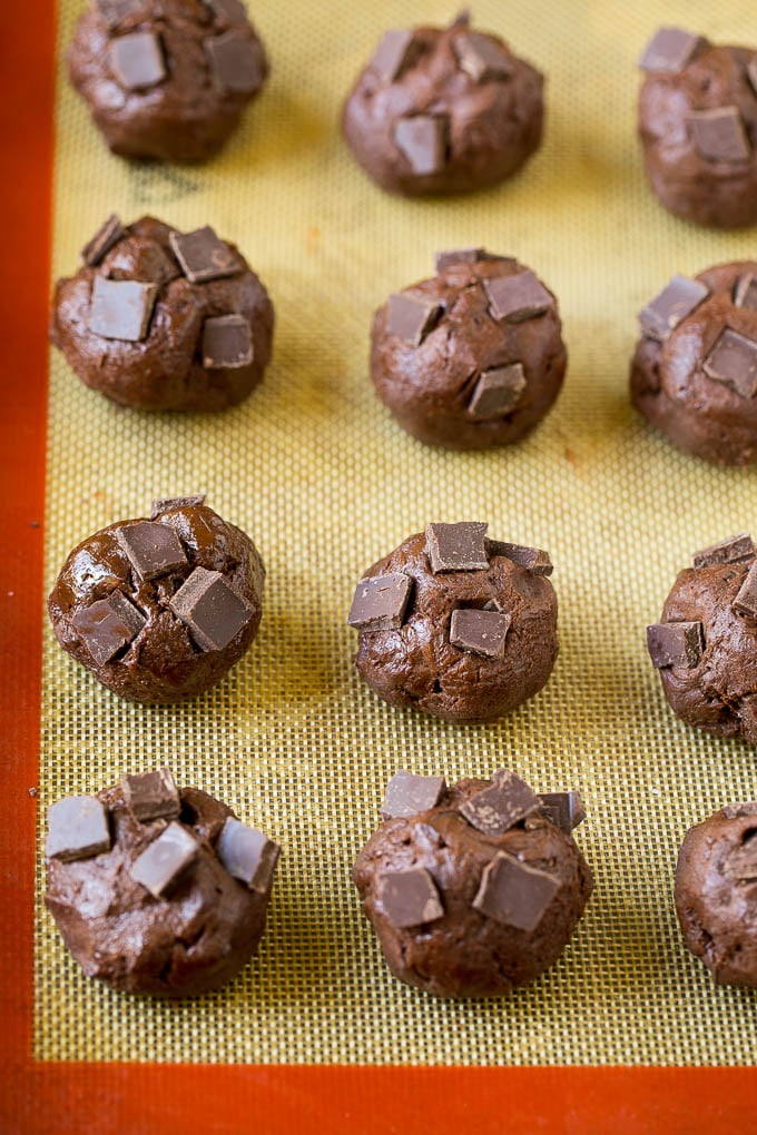 Bolas de masa para galletas con trozos de chocolate presionados en la parte superior.