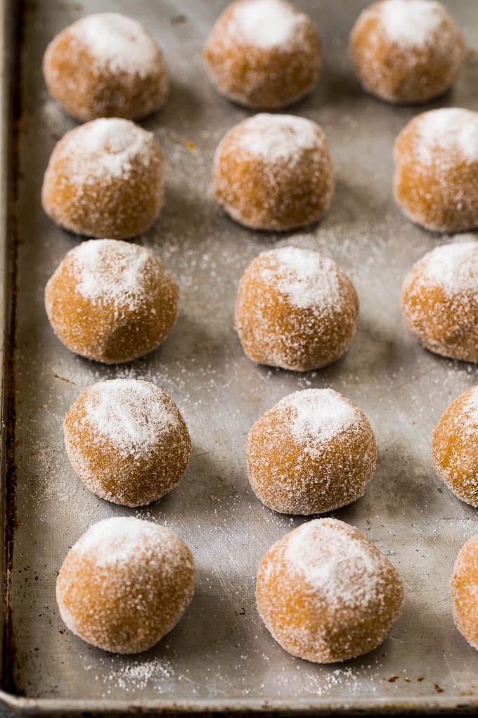 Bolas de masa de galleta enrolladas en azúcar en una bandeja para hornear.