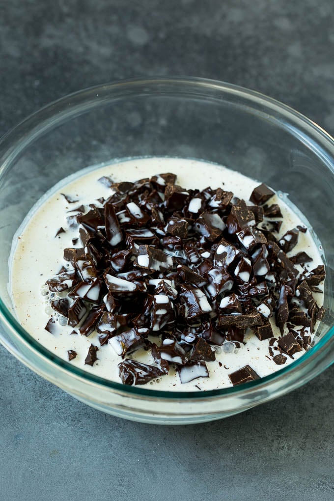 Se vierte crema caliente sobre un montón de chocolate picado.