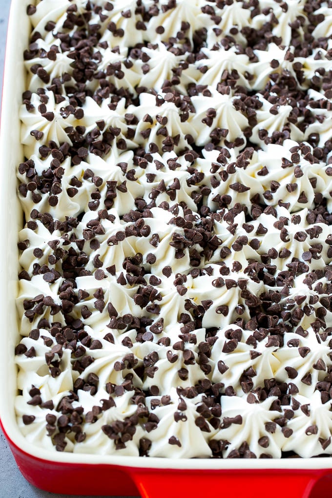Una sartén de lasaña de chocolate cubierta con crema batida y chispas de chocolate en miniatura.