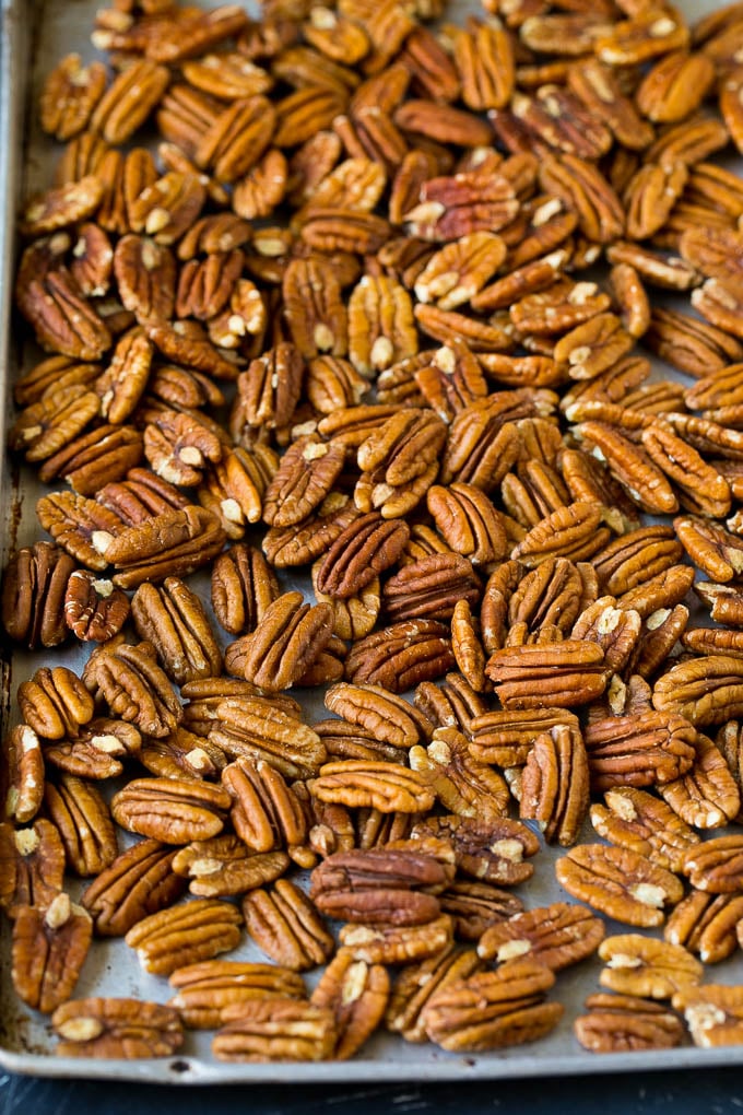 Receta de nueces confitadas | Nueces congeladas | Pacanas dulces #pacana #nueces # merienda # postre #dinneratthezoo Nueces pecanas cortadas por la mitad en una bandeja para hornear.