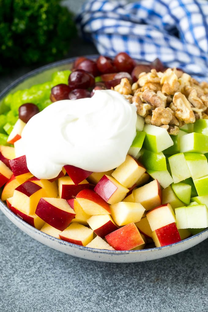 Receta de ensalada Waldorf | Ensalada de manzana | Ensalada de frutas #ensalada #frutas #manzanas #uvas #lunch #Cazuelas online#glutenfree Manzanas, pasas, nueces y apio en un bol cubierto con aderezo cremoso.