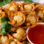 Un plato de wonton frito servido con salsa de chile dulce.