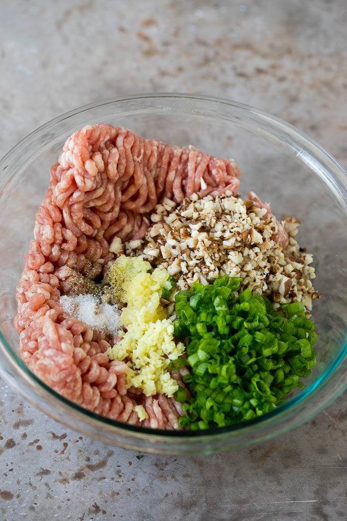 Carne de cerdo molida con champiñones cortados en cubitos y condimentos en un tazón para mezclar.