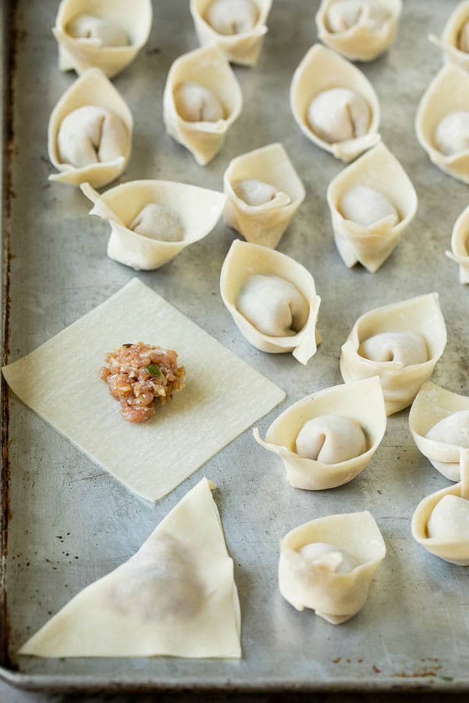 Una envoltura de wonton con una cucharada de mezcla de carne de cerdo molida adentro.