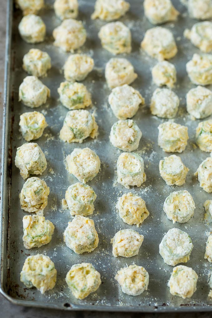 Receta de okra frita #okra #aperitif #sidedish #dinneratthezoo Rodajas de okra empanizadas en una bandeja para hornear.