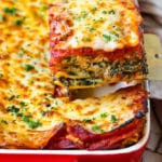 Una espátula que sirve una rebanada de lasaña de espinacas.