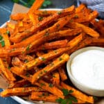 Un plato de batatas fritas con salsa ranch a un lado.