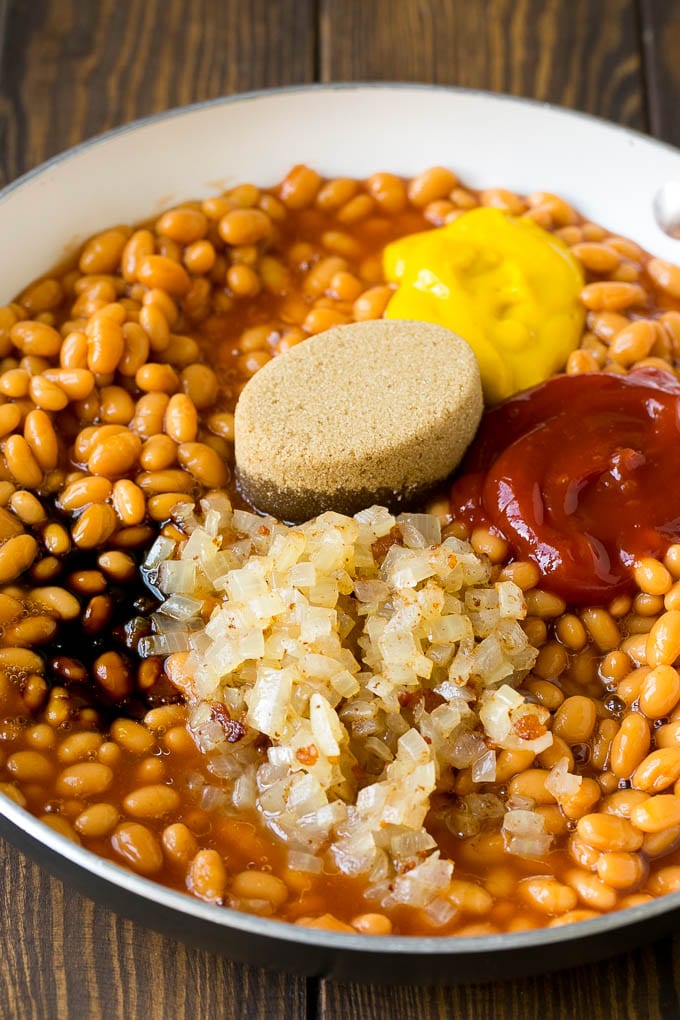 Frijoles en una cacerola con cebolla, melaza, panela, ketchup y mostaza.