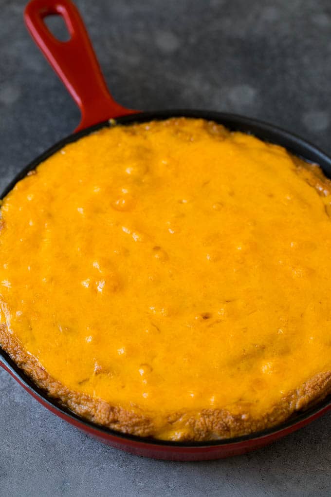 Frijoles fritos al horno cubiertos con queso cheddar derretido.