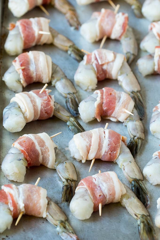 Camarones crudos en una bandeja para hornear envuelta en tocino.