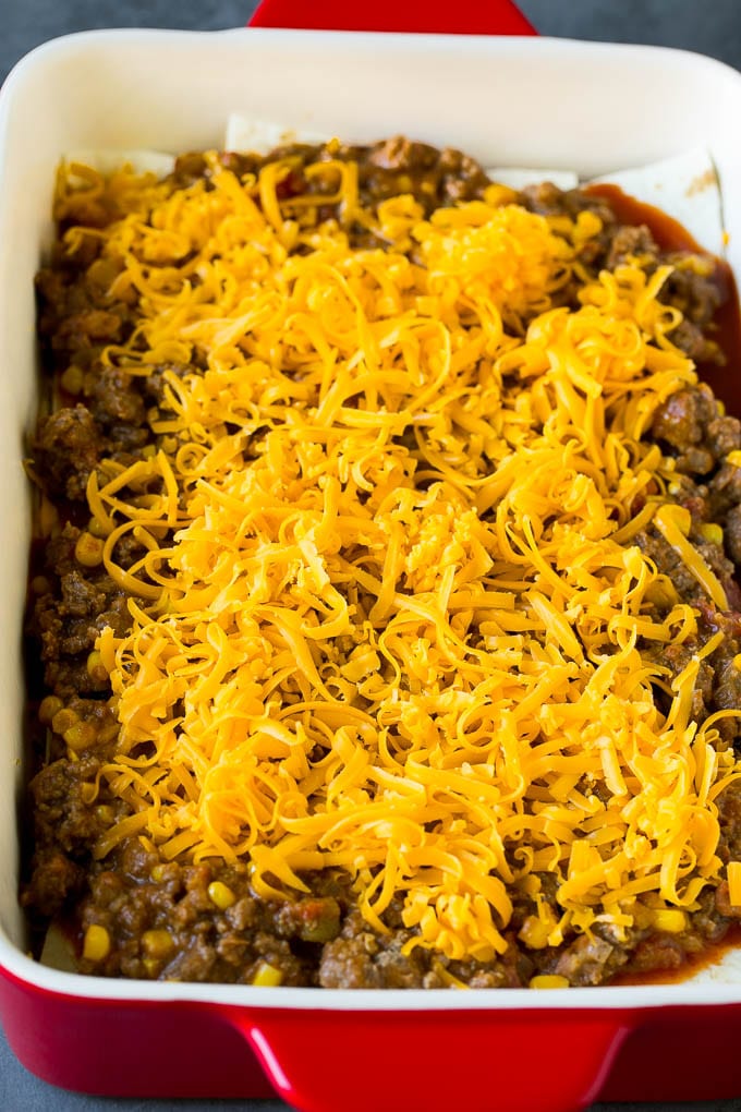Capas de tortillas, carne molida y queso rallado en una fuente para hornear.