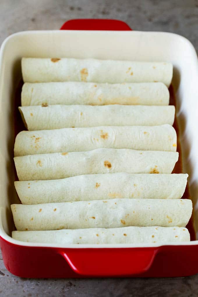Tortillas de harina envueltas alrededor de carne molida en una fuente para hornear.