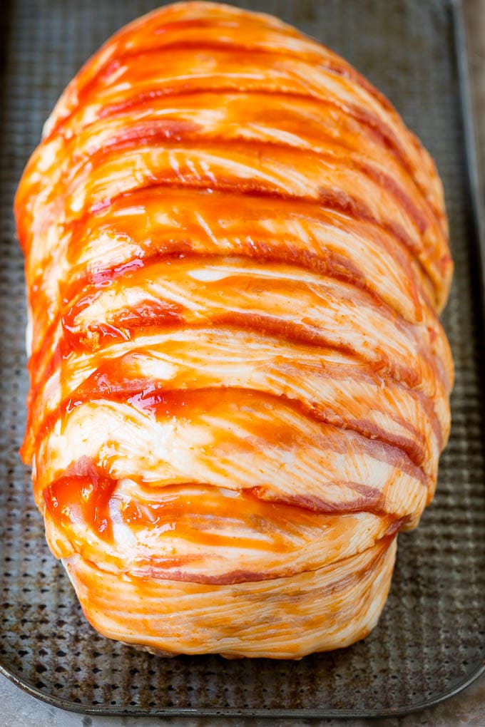 Rebanadas de tocino crudo envueltas alrededor de un bollo de carne molida sazonada.