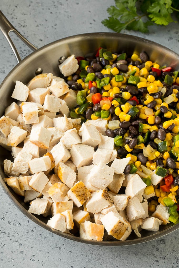 Pollo, maíz, pimientos y frijoles negros en cubitos en una sartén.