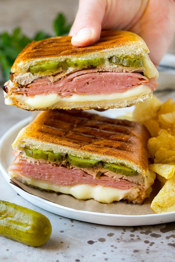 Una mano que sostiene la mitad de un sándwich cubano.