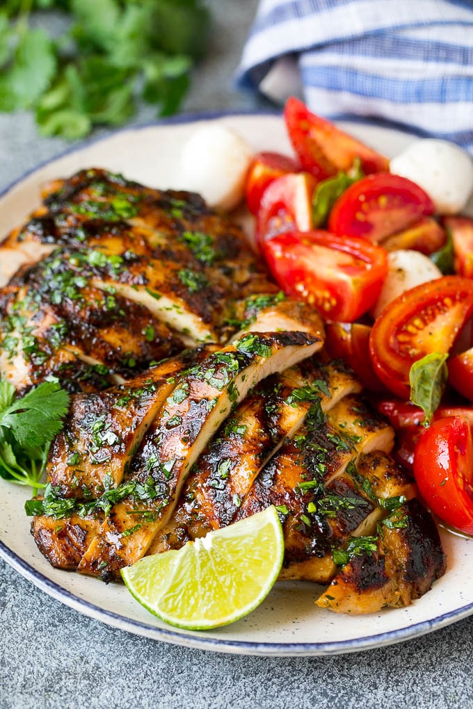 Muslos de pollo en rodajas servidos con ensalada de tomate.
