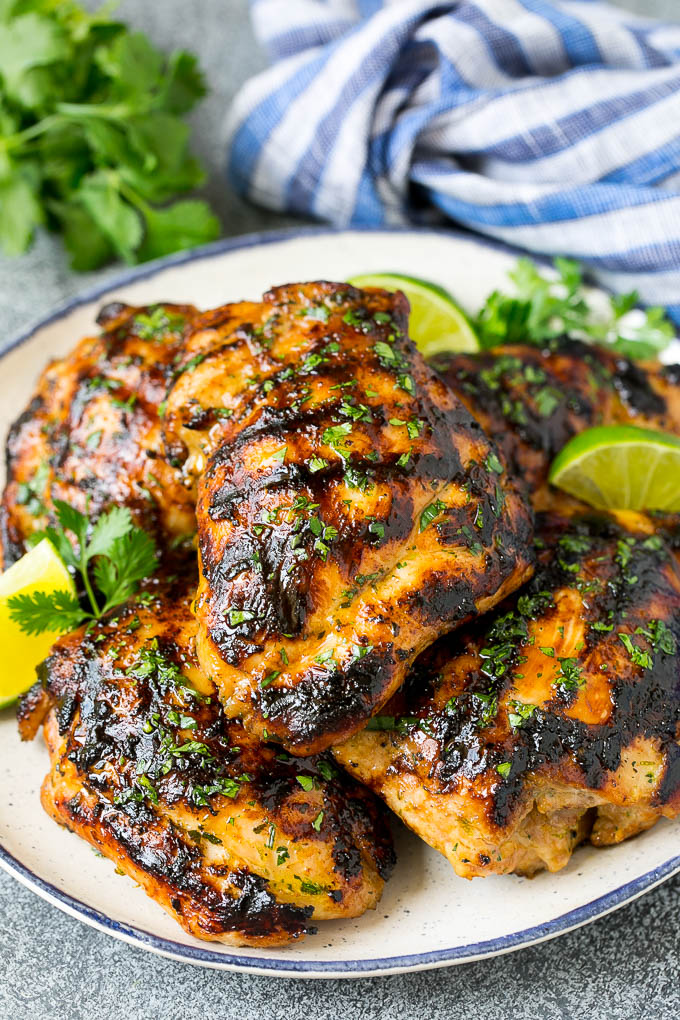 Muslos de pollo a la plancha con guarnición de cilantro y rodajas de lima.