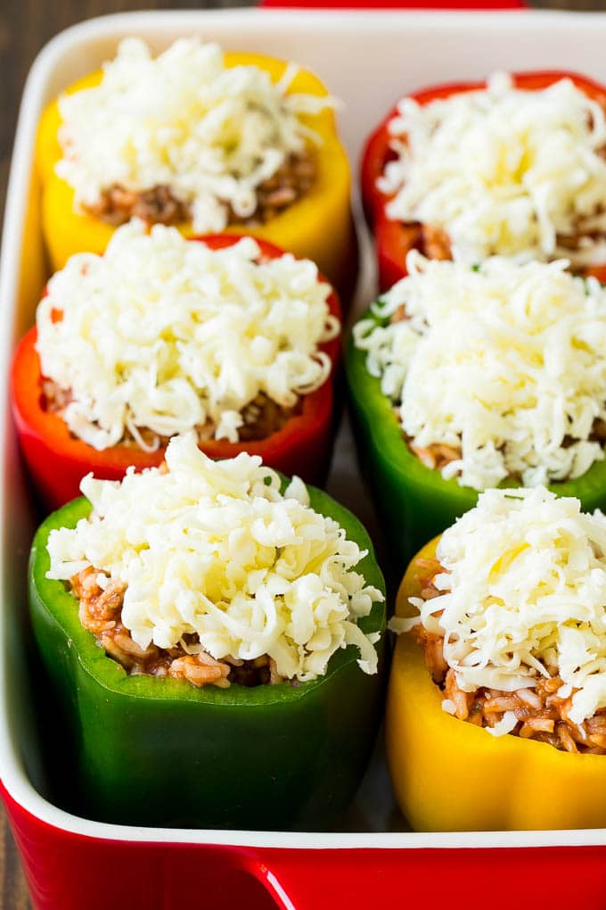 Pimientos rellenos de carne y arroz, aderezados con queso rallado.