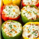 Pimientos rellenos en una fuente para horno cubierta con queso derretido.