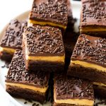 Brownie de mantequilla de maní con una base de brownie de chocolate, glaseado de mantequilla de maní y cobertura de chocolate amargo.