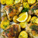 Una sartén de pollo griego y patatas con ajo, hierbas y limón.