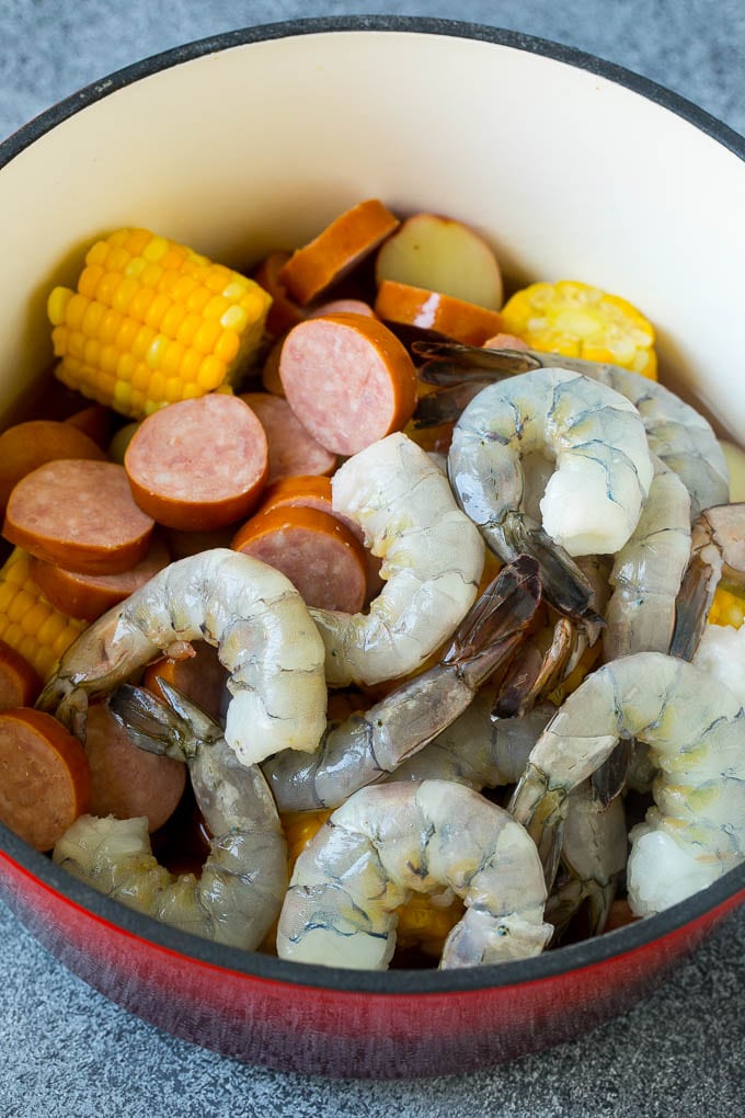 Salchicha, camarones, maíz y papas en una sartén roja.