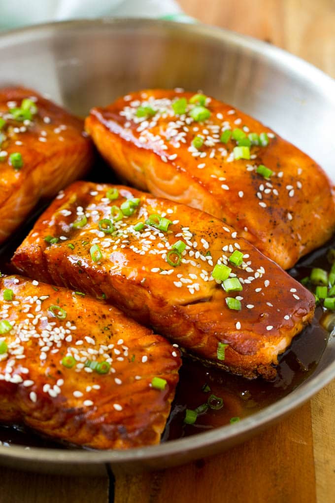 Una sartén llena de filetes de salmón teriyaki cubiertos con semillas de sésamo.