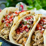 Tacos de cerdo en tortillas de harina cubiertos con pico de gallo.