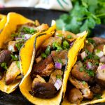 Tacos de carnitas de cocción lenta rellenos de carne, cebolla y cilantro.