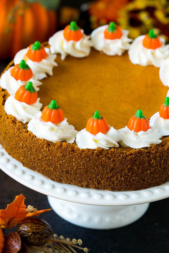 Pastel de queso con pastel de calabaza cubierto con crema batida y calabazas dulces.