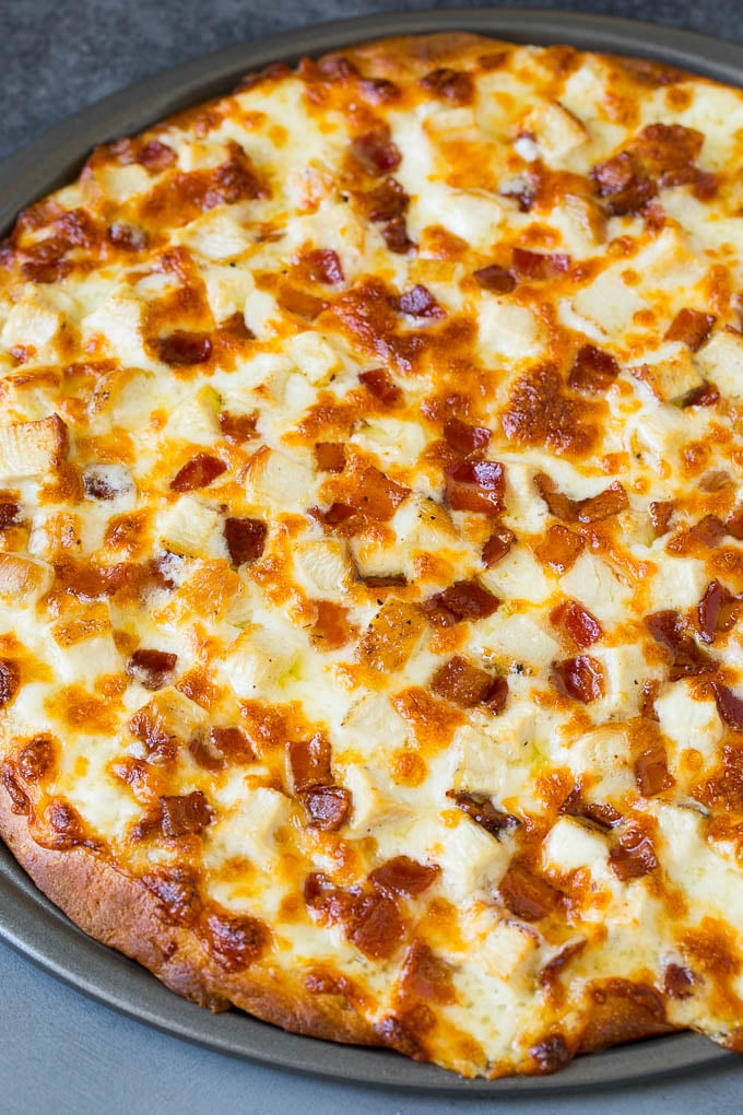 Una pizza horneada cubierta con pollo cortado en cubitos y tocino.