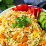 Un plato de arroz frito tailandés aderezado con pepinos y tomates.