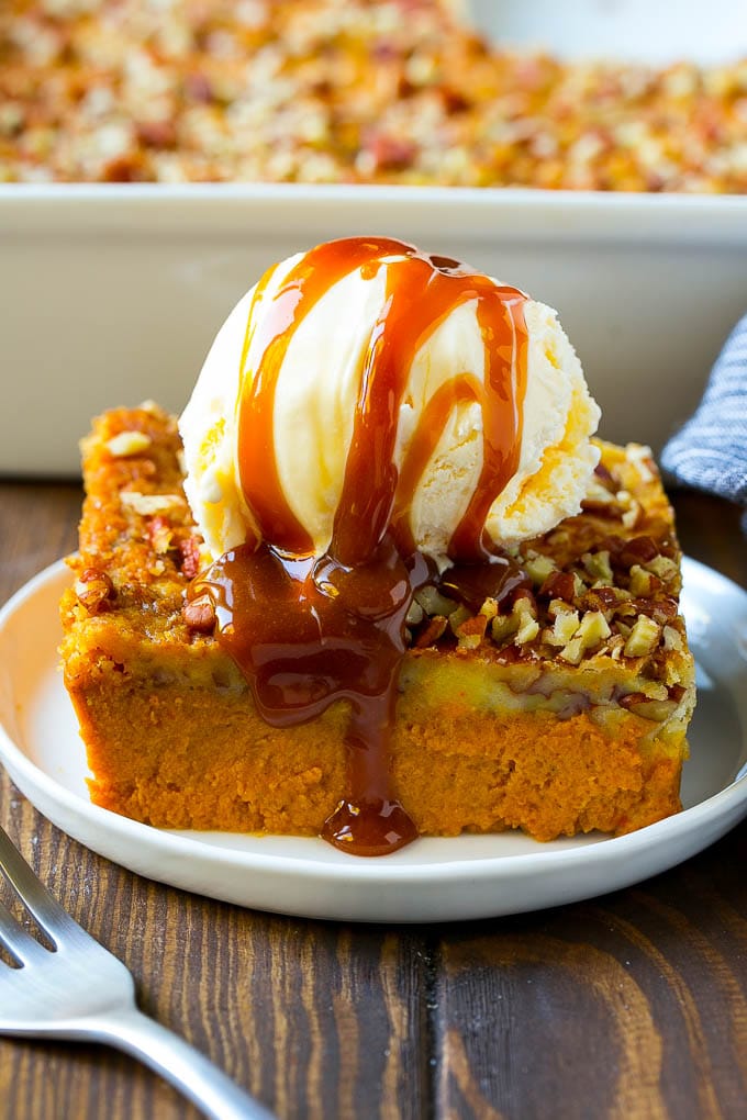 Receta de pastel de calabaza | Pastel de calabaza | Pastel de calabaza # calabaza # pastel # pacanas # otoño # acción de gracias # postre #dinneratthezoo Una rebanada de pastel de calabaza cubierta con helado y salsa de caramelo.