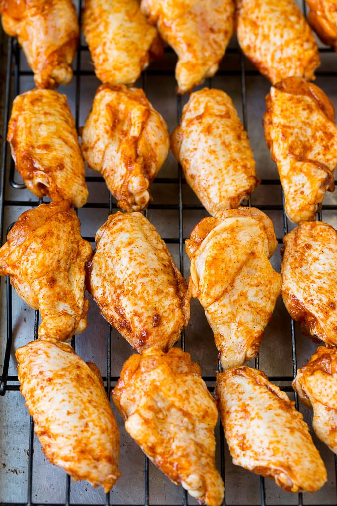 Alitas de pollo cubiertas de especias en una parrilla para cocinar.