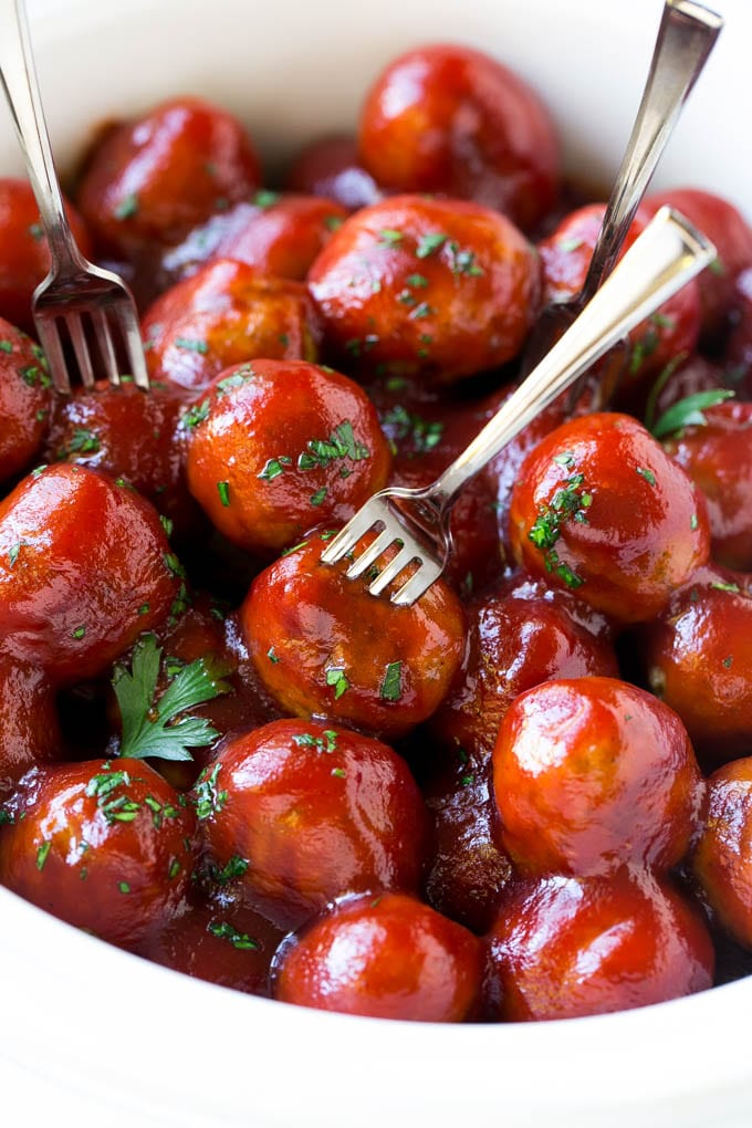 Receta de albóndigas de arándanos | Albóndigas cocidas a fuego lento | Aperitivo de cocción lenta | Crockpot albóndigas #meatballs #cranberry #slowcooker #crockpot #aperetizer #dinneratthezoo Una olla de cocción lenta llena de albóndigas de arándano con tenedores de cóctel.