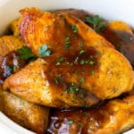 Pechugas de pollo cocidas a fuego lento cubiertas con salsa y perejil.