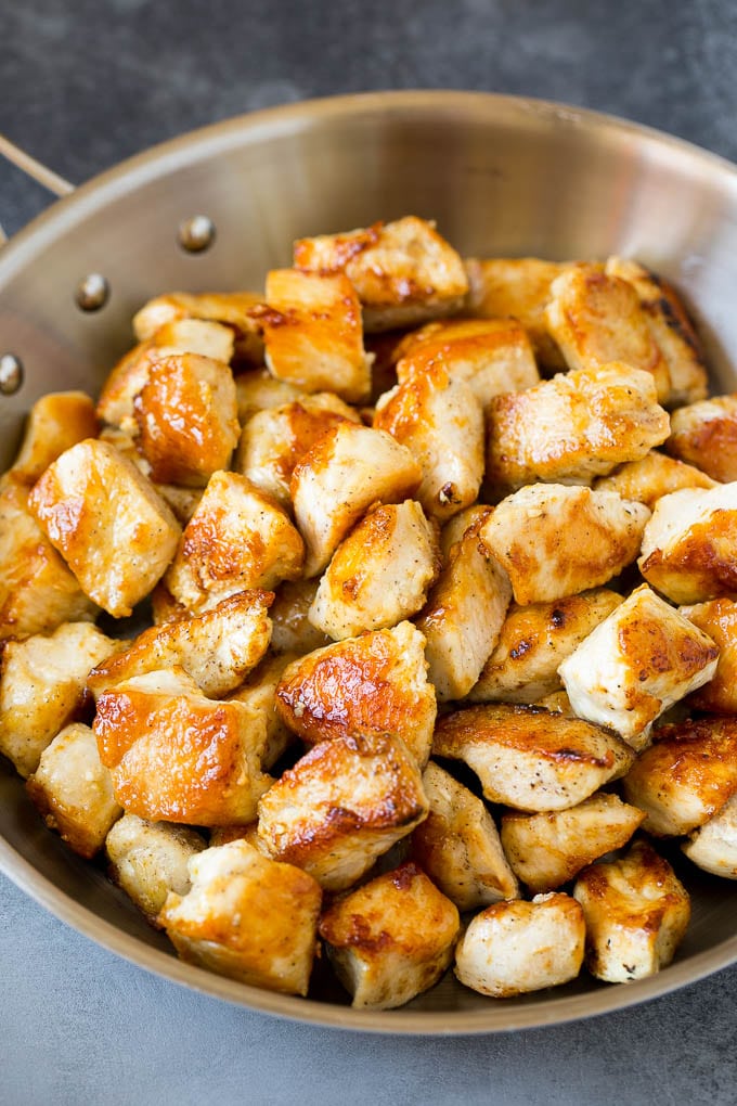 Trozos de pechuga de pollo chamuscados en una sartén.
