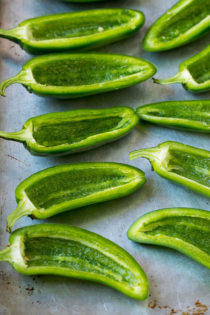 Jalapeños cortados por la mitad y sin corazón en una bandeja para hornear.