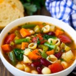 Un plato de sopa de verduras y frijoles, servido con una guarnición de pan.