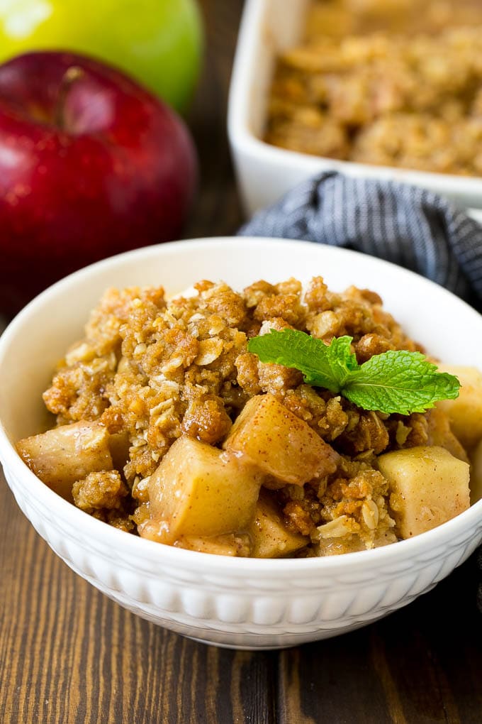 Receta de manzana crujiente |  Postre de manzana #manzanas #postre # hornear # otoño #dinneratthezoo Un cuenco de manzana crujiente adornado con una ramita de menta.
