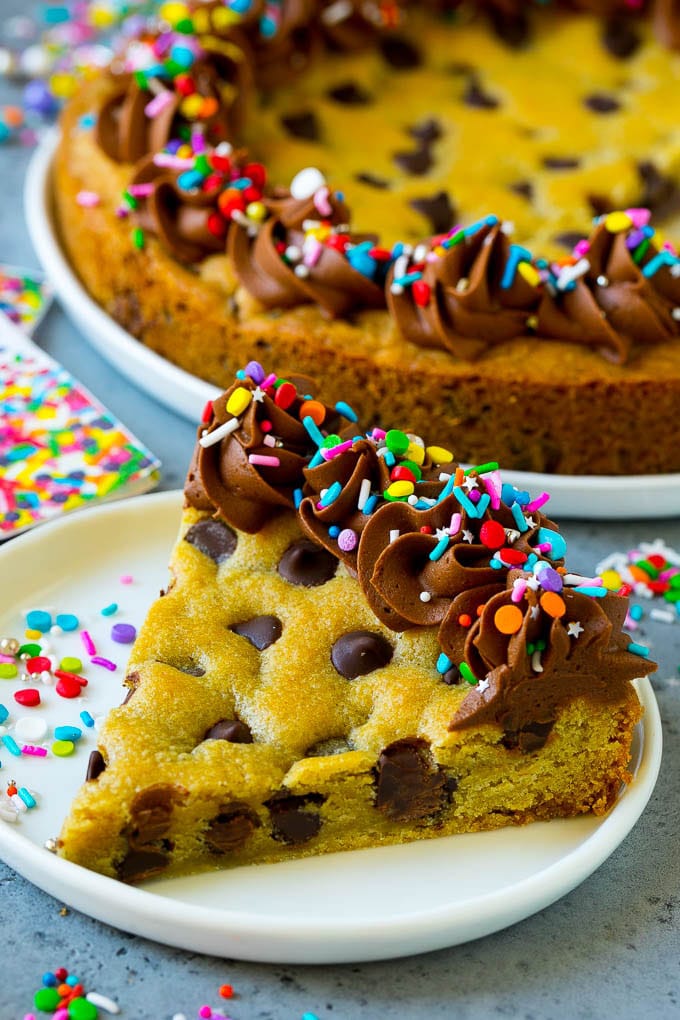 Una rebanada de bizcocho cubierto con una capa de glaseado de chocolate y chispitas de colores.